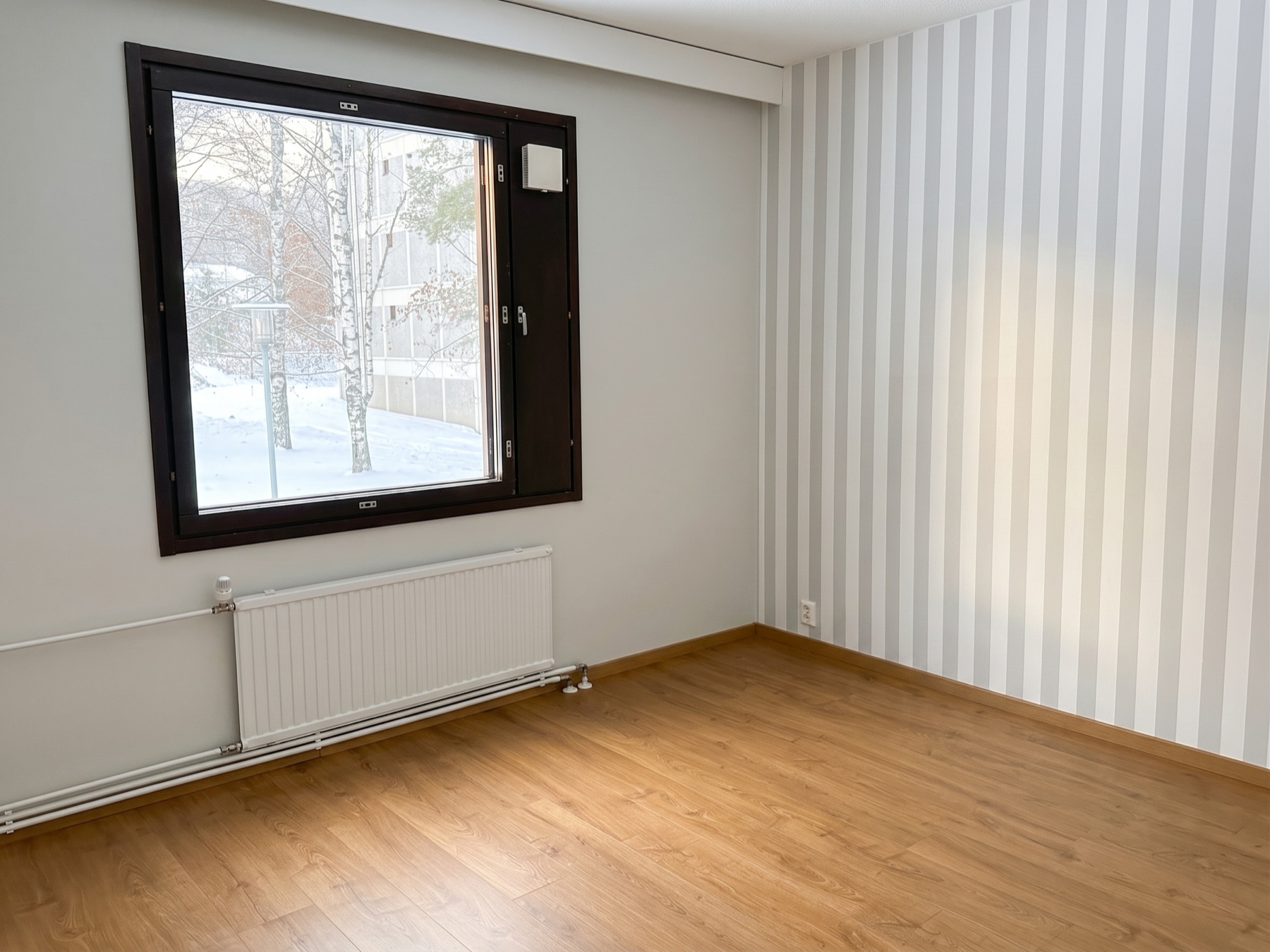 Makuuhuone, puulattia ja ikkuna sisäpihalle